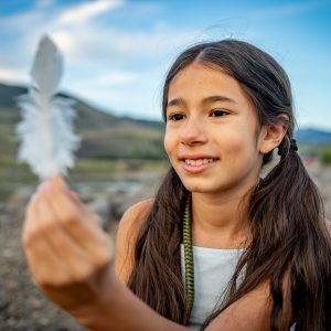 Girl Holding a Feather Outdoors is iD Buzz