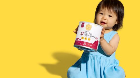 asian baby girl in blue dress holding up a container