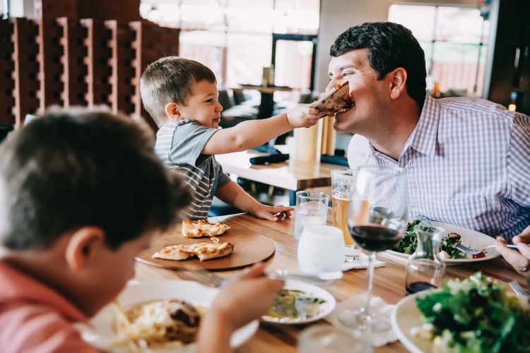 Boy feeding dad pizza in restaurant