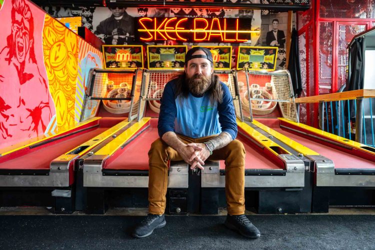 Man Sitting on Skee Ball Game