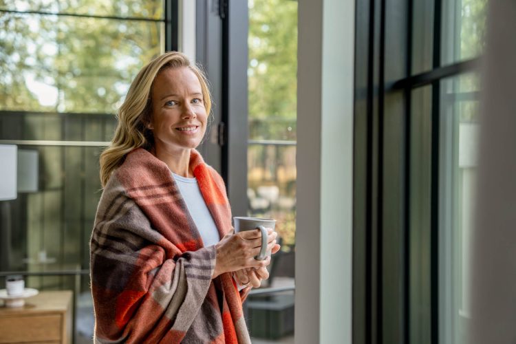 Smiling Woman Wrapped in Blanket Holding Mug