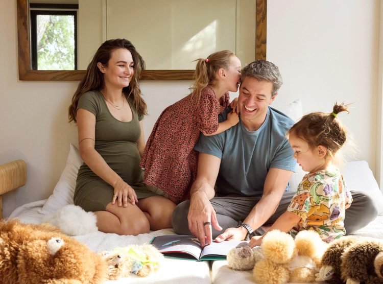 Family on bed reading book and laughing