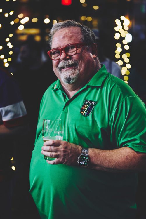 large man wearing red frames green shirt austin