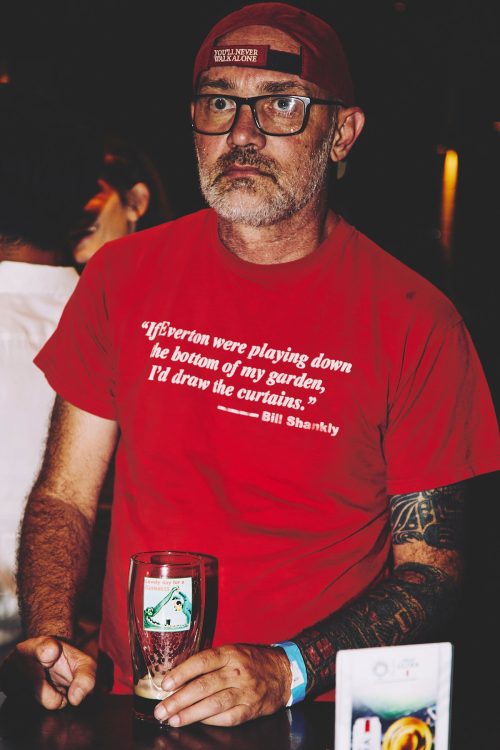 man wearing glasses hat holding pint